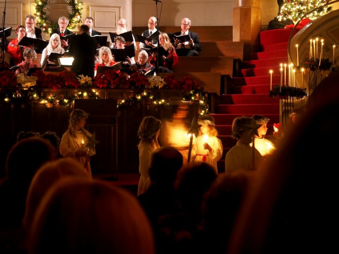 A festive candlelight ceremony with a choir performing at a Seattle church with holiday decorations.